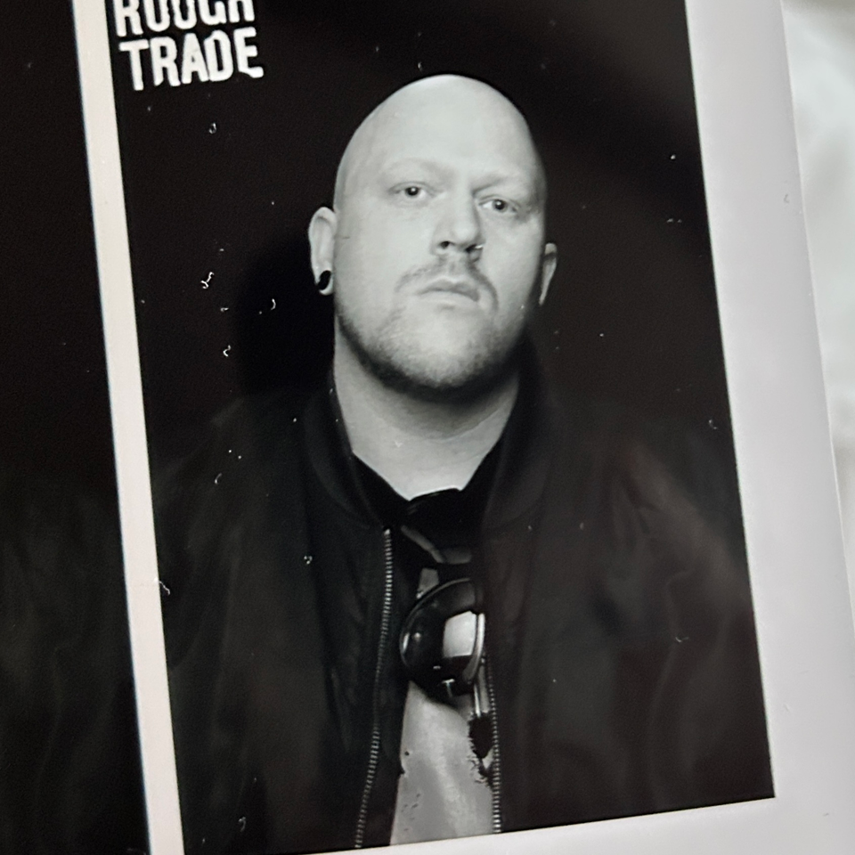 Picture of a bald headed man with black sunglasses with a green stylised glitch effect.